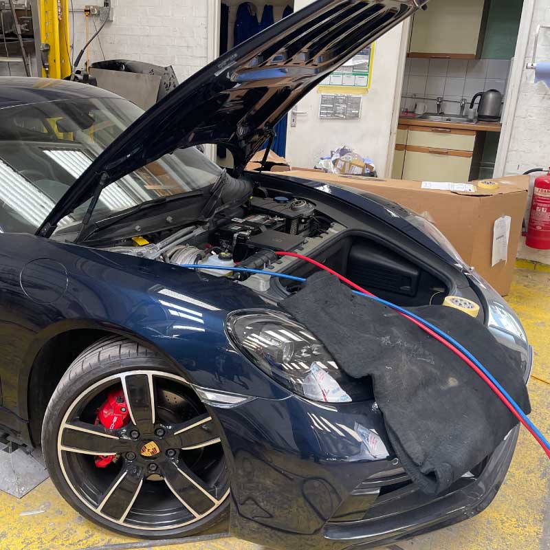 Air con regas hoses connected under the bonnet of a sports car during a service